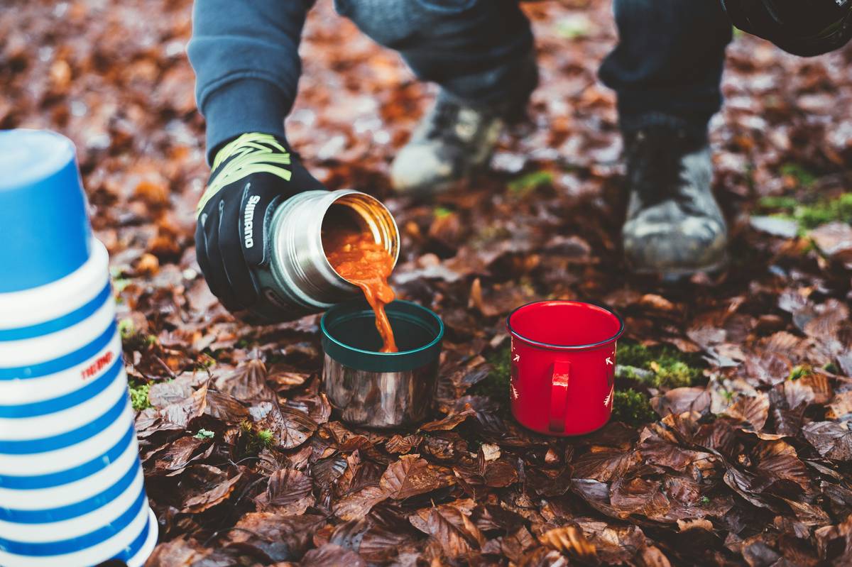Stainless steel insulated to go cups holding white wine outdoors on a picnic blanket